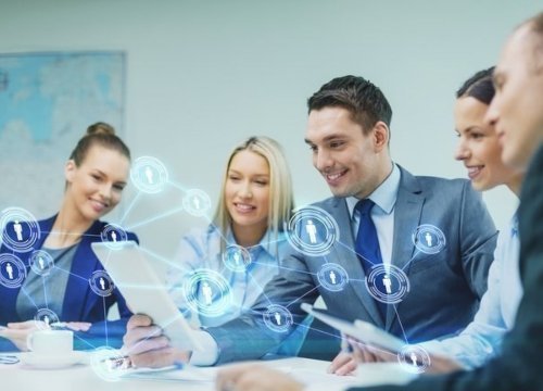 Grupo de personas sonriendo en una reunión, en la imagen se reflejan íconos digitales de personas