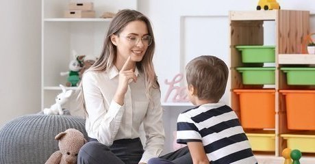 Psicóloga hablando con niño de aproximadamente 5 años en aula de clase
