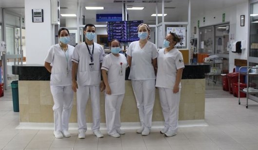 Equipo de profesionales de la salud en un hospital, usando mascarillas y uniformes blancos.