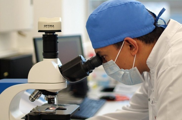 Investigador observando por un microscopio en un laboratorio.