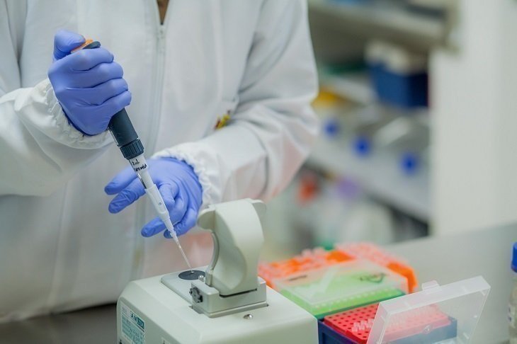 Profesional utilizando micropipeta en laboratorio con instrumentos científicos.