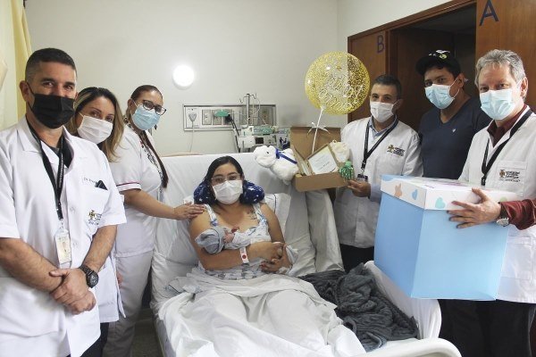Personal médico entregando regalos a una paciente hospitalizada, todos con mascarilla.