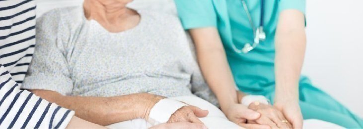 Profesional de salud tomando la mano de una paciente hospitalizada.