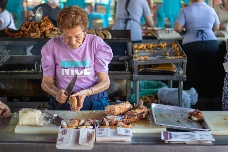 Mujer en su puesto de comida cortando carne
